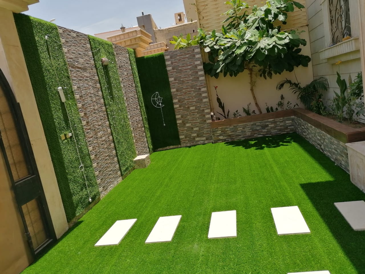 حديقة عشب صناعي مع جدران حجرية